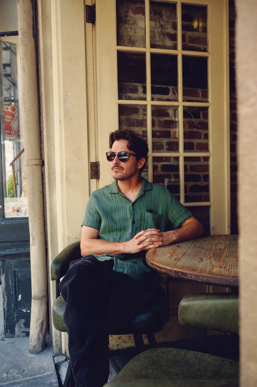 Graham Hill seated outside a French Quarter doorway in sunglasses