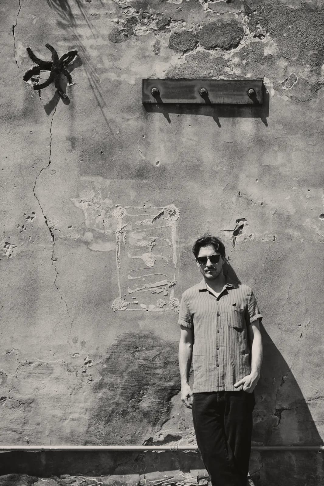 Black-and-white portrait of Graham Hill against a weathered plaster wall